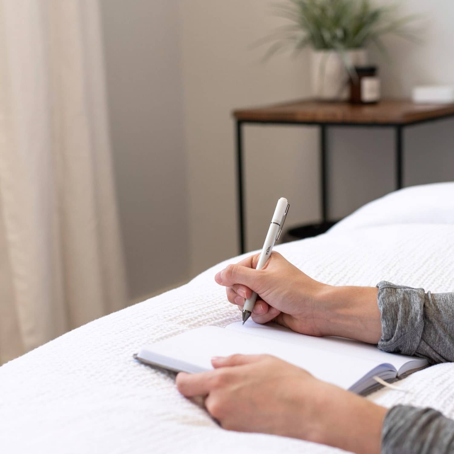 woman writing in journal on bed